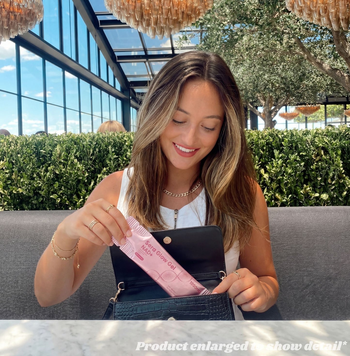 Woman sitting outdoors, holding a pink product packaging